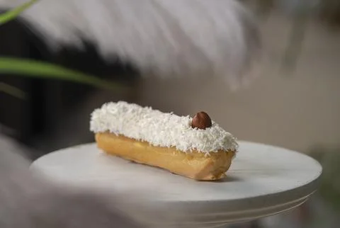 French eclair with coconut crumble hazelnut on a white desk Stock Photos