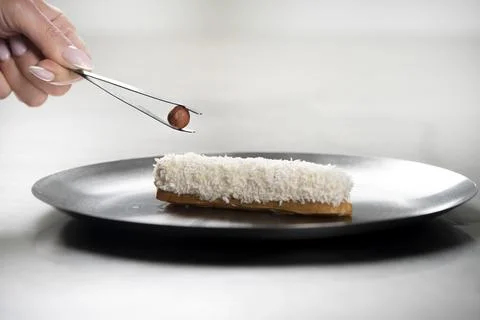 French eclair with coconut crumble hazelnut on a plate. making eclair Stock Photos