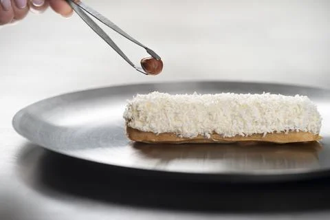 French eclair with coconut crumble hazelnut on a plate .Eclair making Foto stock
