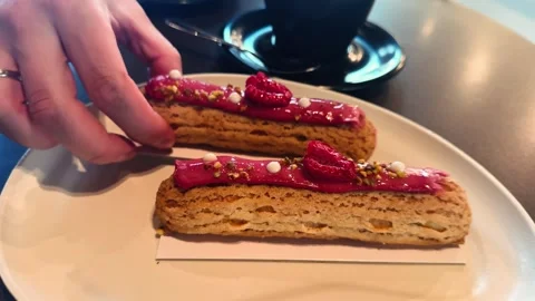 French eclairs with raspberry glaze and creamy filling served on a plate. Stock Footage 336385522