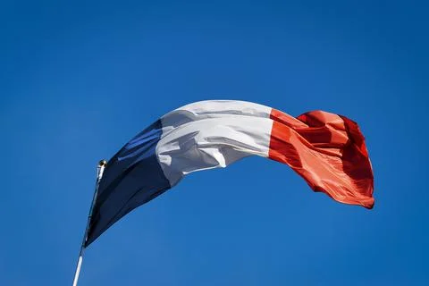 French Flag Blowing in the Wind on Clear Blue Sky - Bottom view Stock Photos