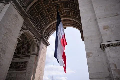 French flag flying under Arc de Triomphe in Paris 스톡 사진