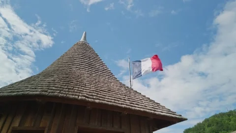 French flag waving next to a historic wooden shingle roof Stock-Footage 336909977