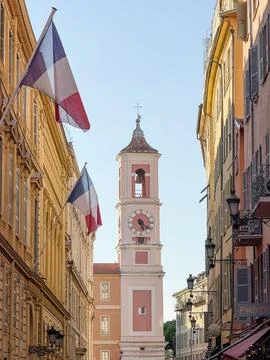 French Flags Framing Historic Clock Tower on a Sunny Street in Nice Old Town Stock Photos