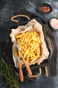 French fries. Tasty French fries server on parchment paper on wooden cutting  Stock Photos