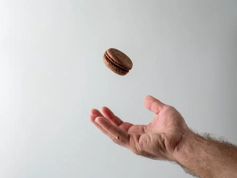 French macaron is falling into man's hand Stock Photos