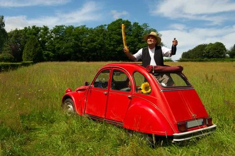 French man with his typical red car French man is holding bread and wine i... Stock Photos