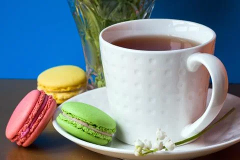 French multicolored cakes macarons and a cup of tea. A bouquet of lily of the Stock Photos
