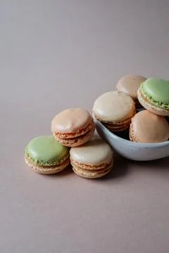 French multicolored mini macarons in a small bowl on beige background close u Stock Photos