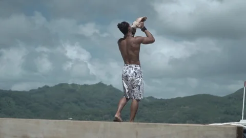 French Polynesian Man blowing shell on dock Stock Footage 92821309