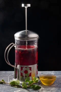 French press berry tea with mint and honey on a black background Foto stock
