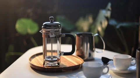 French press coffee maker and cups set on a table with natural light Stock Footage 338990750