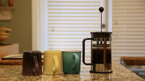 A french press on a kitchen counter top being pressed followed by coffee being Stock Footage 99162033