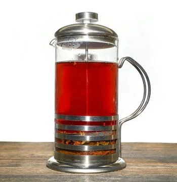A French press for making coffee and tea, filled with black tea, is on the ta Stock Photos