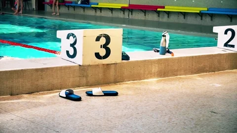A French swimming pool with numbered starting blocks, sandals on the poolside Stock Footage 316923000