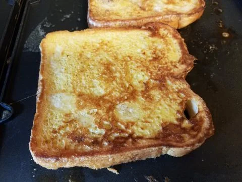 French toast bread with egg and cinnamon cooking on grill Stock Photos