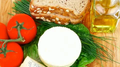 Fresh aged french cheeses chops on big cutting board with tomatoes and rye bread Stock Footage