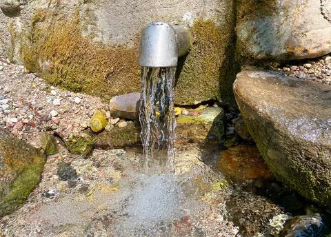 A fresh and cool spring flows from the ground. Cool and delicious spring water Stock Photos