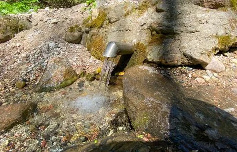 A fresh and cool spring flows from the ground. Cool and delicious spring water Stock Photos