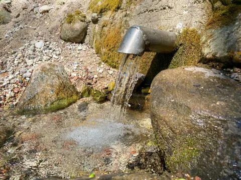 A fresh and cool spring flows from the ground. Cool and delicious spring water Stock Photos