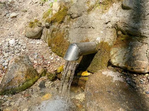 A fresh and cool spring flows from the ground. Cool and delicious spring water Stock Photos
