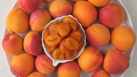 Fresh and dried apricots rotating on a plate Stock Footage 343433851