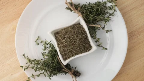Fresh and dried thyme rotating on a white plate Stock Footage 347099812