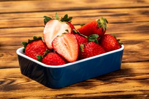 Fresh and split strawberries on rustic wooden table. Foto stock