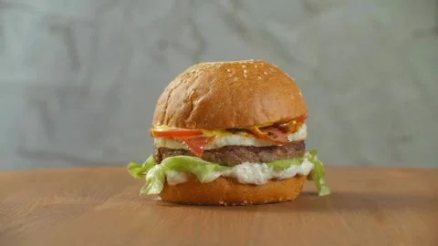 Fresh appetizing hamburger rotating on black background. lettuce, onion, pickled Stock Footage 336579369