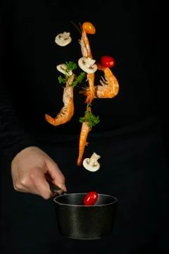 Fresh appetizing shrimp fall into a black pan on a dark background Stock Photos