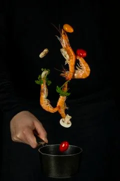 Fresh appetizing shrimp fall into a black pan on a dark background Stock Photos