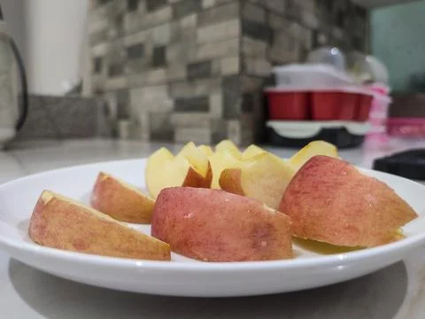 Fresh apple slices rest on a clean white plate Stock Photos