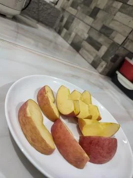 Fresh apple slices rest on a clean white plate Stock Photos