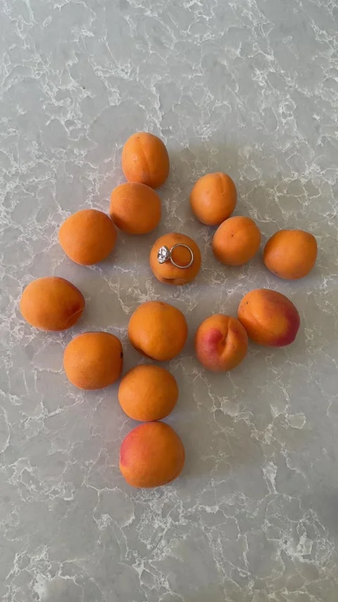 Fresh apricots arranged on marble with platinum band ring hand vertical video Stock Footage 317021953