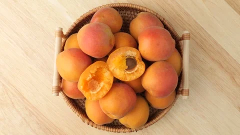 Fresh apricots rotating inside wicker basket on wooden surface Vidéo 348307676