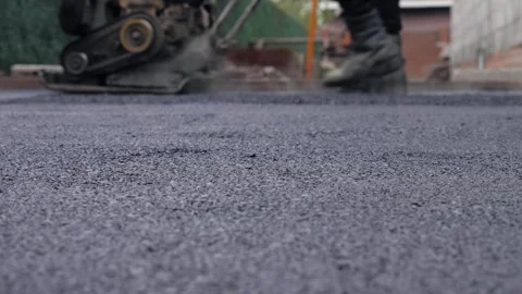 Fresh Asphalt Surface With Worker Using Vibratory Plate In Background Stock Footage 334795024