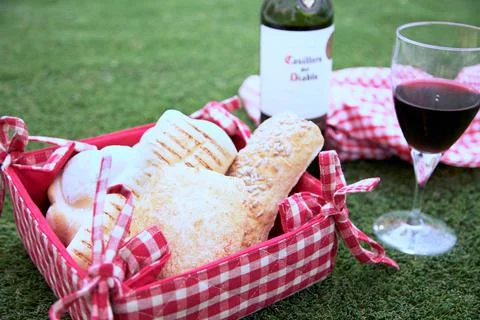 Fresh assorted bread in red and white checkered basket, with red wine 写真素材