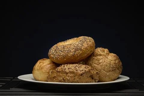 Fresh assorted bread rolls stacked on a plate with colorful studio light Stock-Fotos