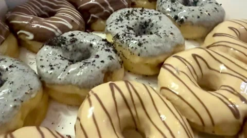 Fresh assorted donuts with chocolate drizzle and powdered sugar Stock Footage 330436285