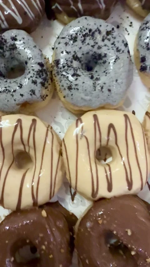 Fresh assorted donuts with chocolate drizzle and powdered sugar Stock Footage 330436288