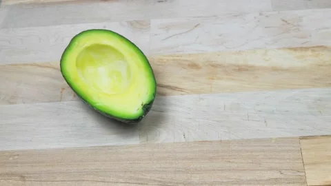 Fresh avocado in the kitchen. A man puts half an avocado on a wooden cutting Video stock 222637013