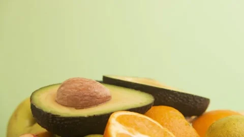 Fresh avocado, oranges, apples fruit on green background Stock Footage 246664368