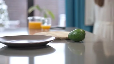 A Fresh Avocado Resting on the Kitchen Counter Surrounded by Juice and a Relaxed Stock Footage 293487641