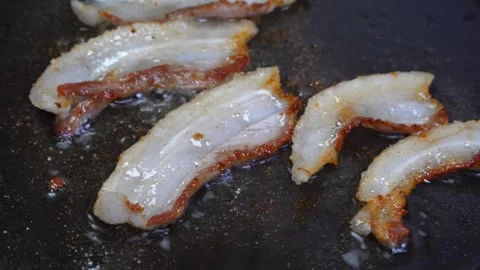 Fresh Bacon in frying pan shrinks and puckers as it cooks. 스톡 동영상 334643194