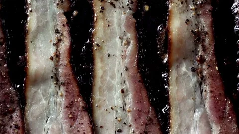 Fresh Bacon in frying pan shrinks and puckers as it cooks. 스톡 동영상 334643223