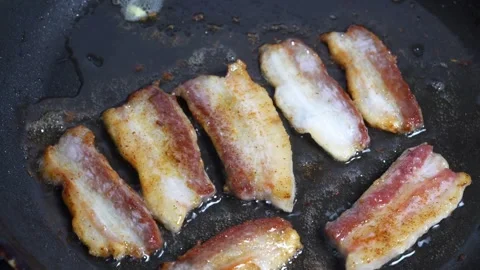Fresh Bacon in frying pan shrinks and puckers as it cooks. 스톡 동영상 334643252