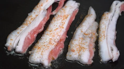 Fresh bacon squirts in the pan. close-up of bacon Stock Footage 122030276