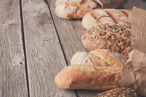 Fresh baguettes and bread rolls on a rustic wooden table Stock Photos