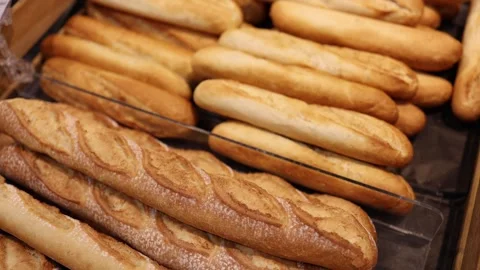 Fresh baguettes and crusty bread arranged in supermarket bakery display Stock Footage 345358628