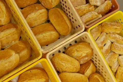 Fresh baked bread displayed in plastic baskets at bakery shop, top-down view. 写真素材